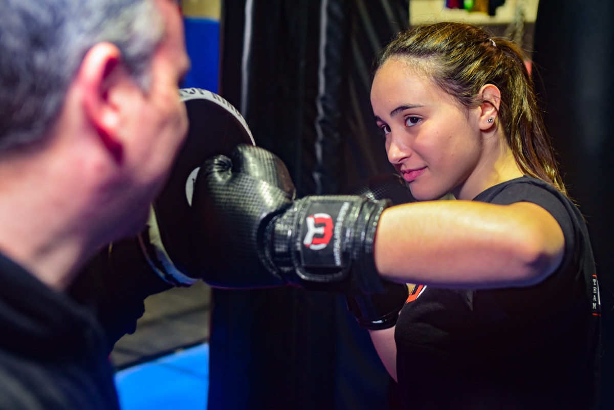 Instructor de Warriors Barcelona sujetando la manopla mientras una alumna golpea en una sesión de entrenador personal