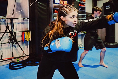 Alumna golpeando con guantes en una clase de kickboxing en Warriors Barcelona
